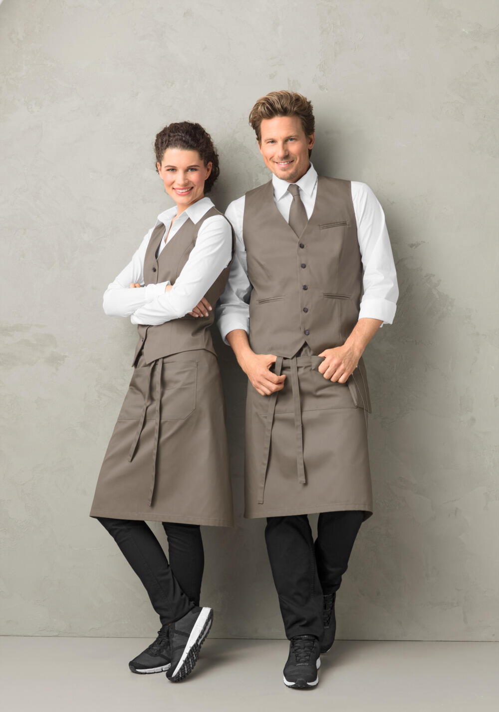 JOBELINE LUSINI Solutions GmbH Women's vest Bistro Damen Weste Bistro Women's vest Bistro; Size 34; taupe Damen Weste Bistro; Kleidergröße 34; taupe 65 % polyester, 35 % cotton. 60°C wash. Classic service waistcoat for ladies with adjustable back strap to adjust the width at the waist, 5-button placket and two piped pockets. Comfortable cut and fully lined. Particularly hard-wearing and easy-care blended fabric. Back length: 56 cm for size 36. 65 % Polyester, 35 % Baumwolle. 60°-Wäsche. Klassische Serviceweste für die Dame mit verstellbarem Rückenriegel zur Weitenregulierung in der Taille, mit 5-Knopfleiste und zwei paspelierten Taschen. Komfortabel geschnitten und komplett gefüttert. Besonders strapazierfähiges und pflegeleichtes Mischgewebe. Rückenlänge: 56 cm in Gr 36