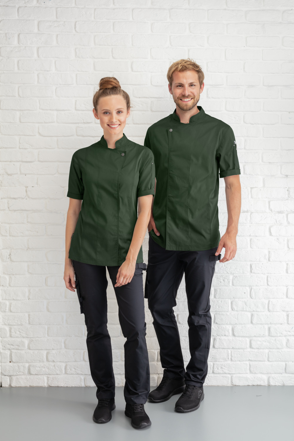 JOBELINE LUSINI Solutions GmbH Women's chef's jacket Carter short-sleeved Damen Kochjacke Carter Kurzarm Women's chef's jacket Carter short-sleeved; Size 38; dark olive Damen Kochjacke Carter Kurzarm; Kleidergröße 38; dunkeloliv 65 % polyester, 35 % cotton. 150 g/m². 60 °C wash. Short-sleeved women's chef jacket made of extra-lightweight but sturdy fabric. With stand-up collar, breathable mesh inserts on the side, two-section upper arm pocket and bib apron loop in the neck. Closes with snaps in a concealed snap placket.  Slightly waisted cut. Back length: 68 cm for size 36. 65 % Polyester, 35 % Baumwolle. 150 g/m². 60°-Wäsche Kurzärmlige Damenkochjacke aus extra leichtem, aber robustem Gewebe. Mit Stehkragen, atmungsaktiven Mesh-Einsätzen an der Seite, zweigeteilter Oberarmtasche und Latzschürzenschlaufe im Nacken. Verschließbar mit Druckknöpfen in einer verdeckten Druckknopfleiste.  Leicht tailliert geschnitten. Rückenlänge: 68 cm in Gr. 36