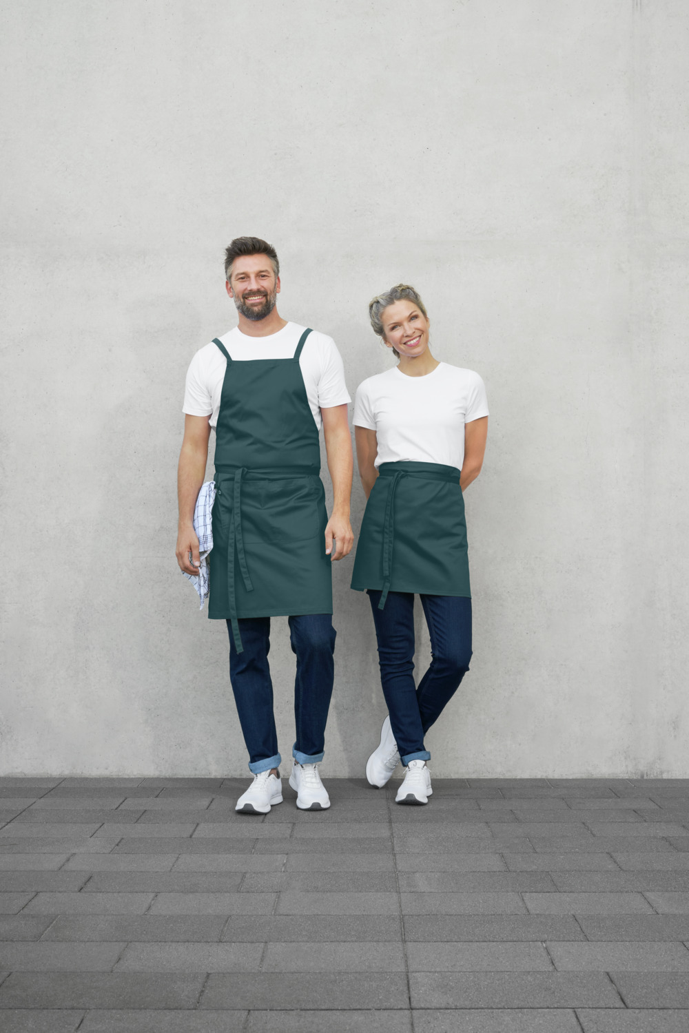 JOBELINE LUSINI Solutions GmbH Bib apron Botero 88x80 cm (LxW) Latzschürze Botero 88x80 cm (LxB) Bib apron Botero 88x80 cm (LxW); 88x80 cm (LxW); petrol green Latzschürze Botero 88x80 cm (LxB); 88x80 cm (LxB); petrolgrün 65 % polyester, 35 % cotton. 200 g/m². 60°C wash. Classic bib apron made of high-quality, robust blended fabric. With fixed apron fabric straps that are crossed at the back to relieve pressure on the neck. With a tea towel loop, pen flap and a large two-part pocket with space for a mini tablet. Particularly hard-wearing, easy-care and easy-iron. Pocket dimensions: 22x19 cm and 22x15 cm (LxW). 65 % Polyester, 35 % Baumwolle. 200 g/m². 60°-Wäsche. Klassische Latzschürze aus hochwertigem und robustem Mischgewebe. Mit festen Stoffbändern aus Schürzenstoff, die zur Entlastung des Nackens im Rücken gekreuzt werden. Mit Geschirrtuchschlaufe, Stiftlasche und einer großen zweigeteilten Tasche, die Platz für ein Tablet im Mini-Format bietet. Besonders strapazierfähig, pflege- und bügelleicht. Taschenmaße:  22x19 cm und 22x15 cm (LxB)